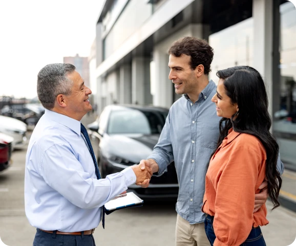 Car dealership handshake with couple